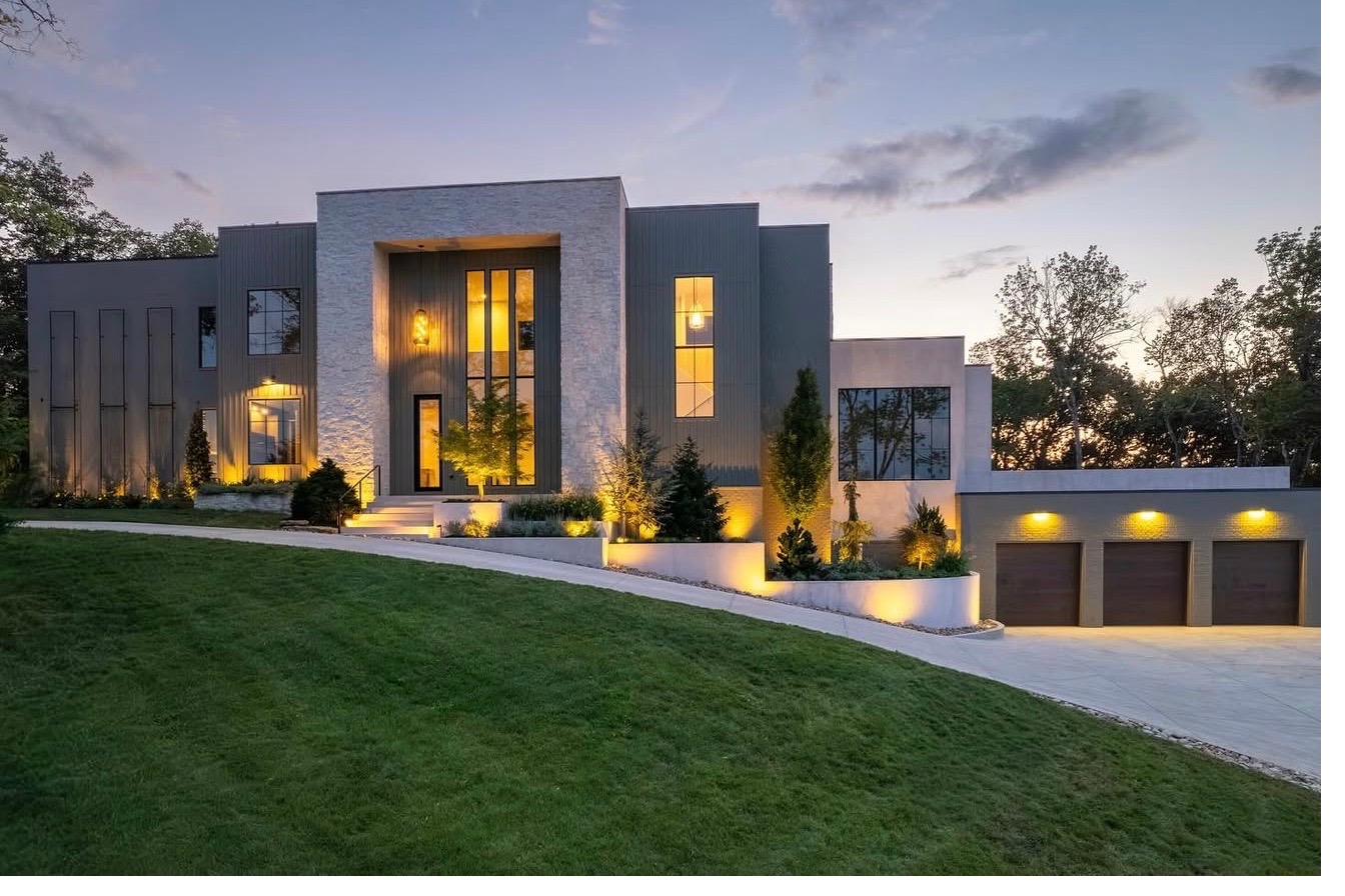 Modern Nashville estate with custom landscape lighting and layered evergreen plantings at twilight